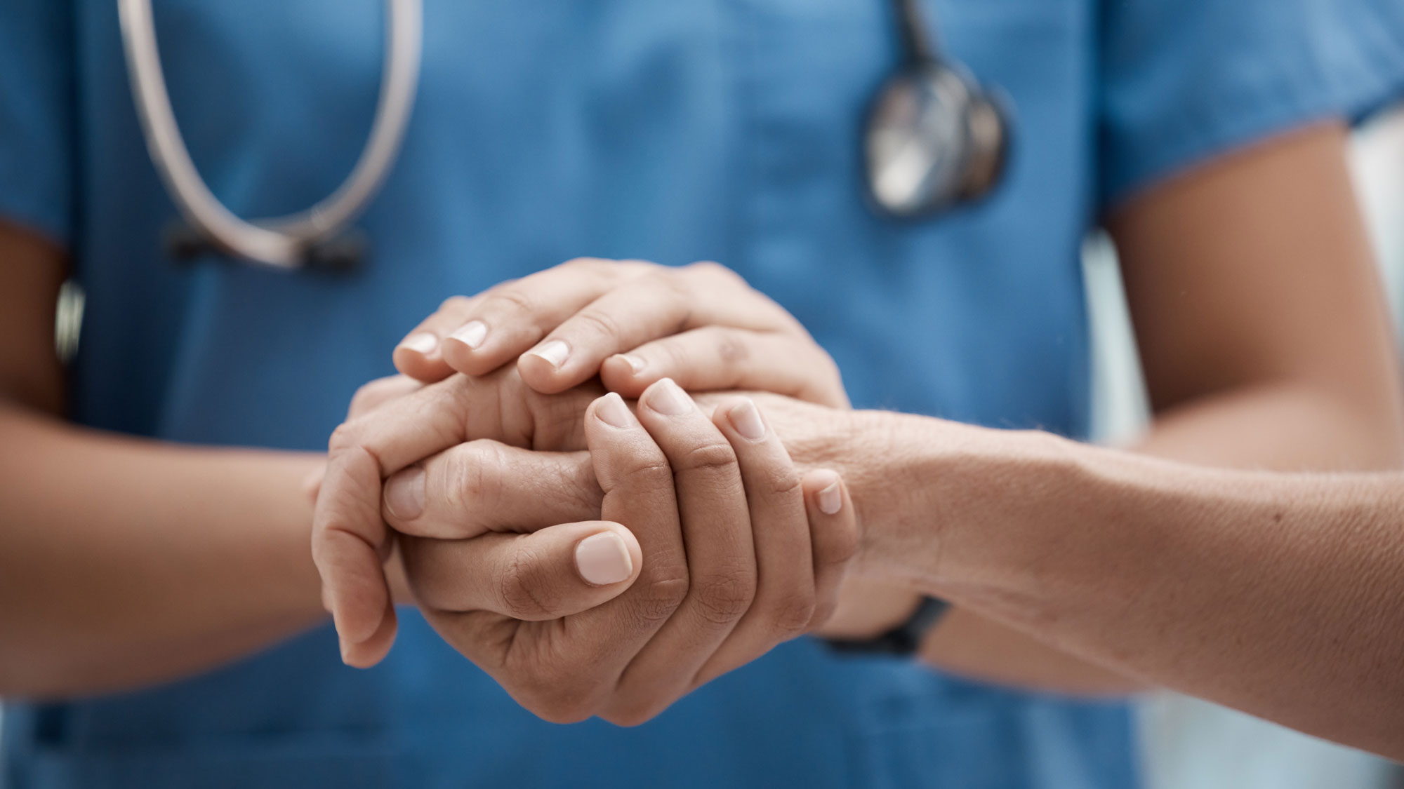 Eine Krankenschwester hält die Hand eines Patienten